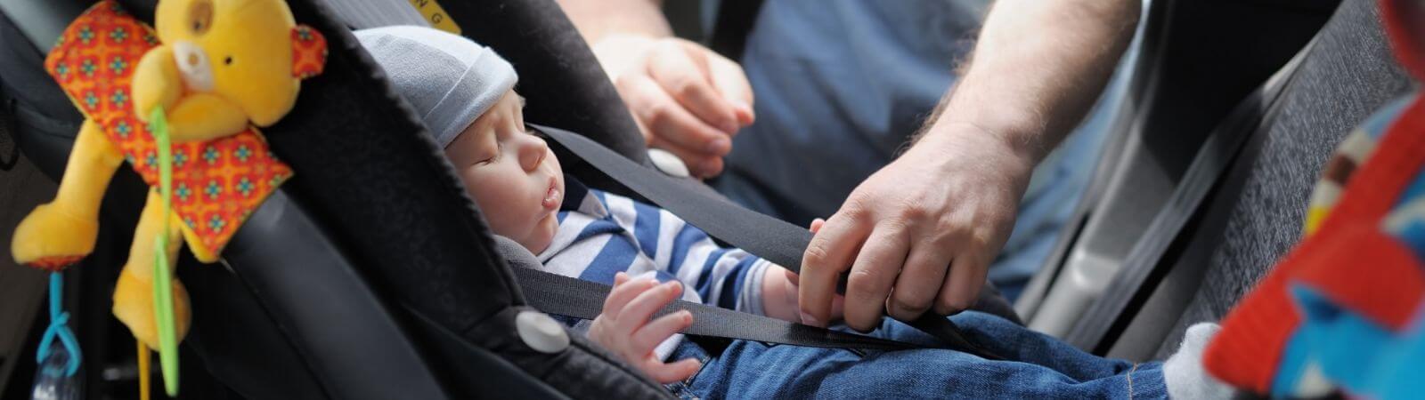 Kiedy zmienić nosidełko na fotelik samochodowy – niemowlę śpi w nosidełku w samochodzie 