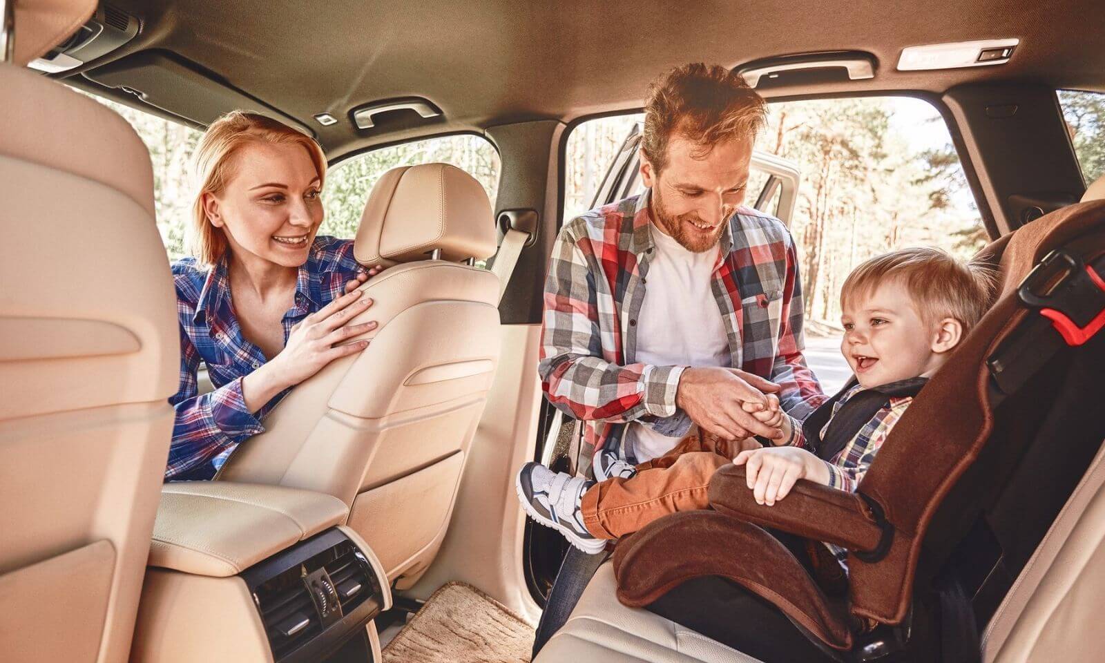 Jaki fotelik samochodowy – uśmiechnięci rodzice w aucie z małym dzieckiem w foteliku