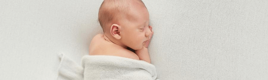 Jakie pieluchy dla noworodka – śpiące dziecko okryte kocykiem