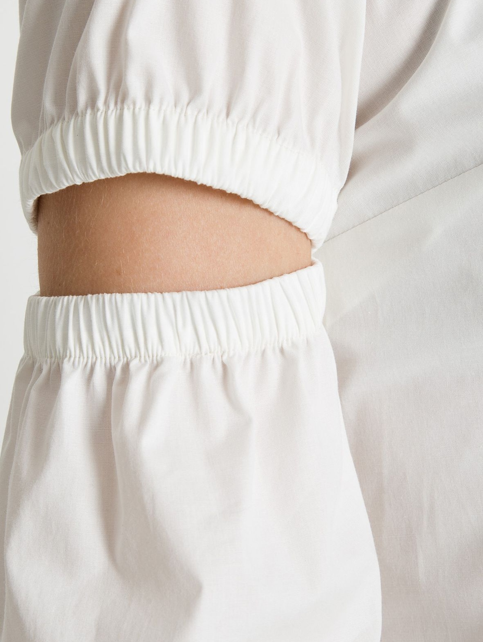 Bluzka damska biała - długi rękaw z ozdobnymi rozcięciami
