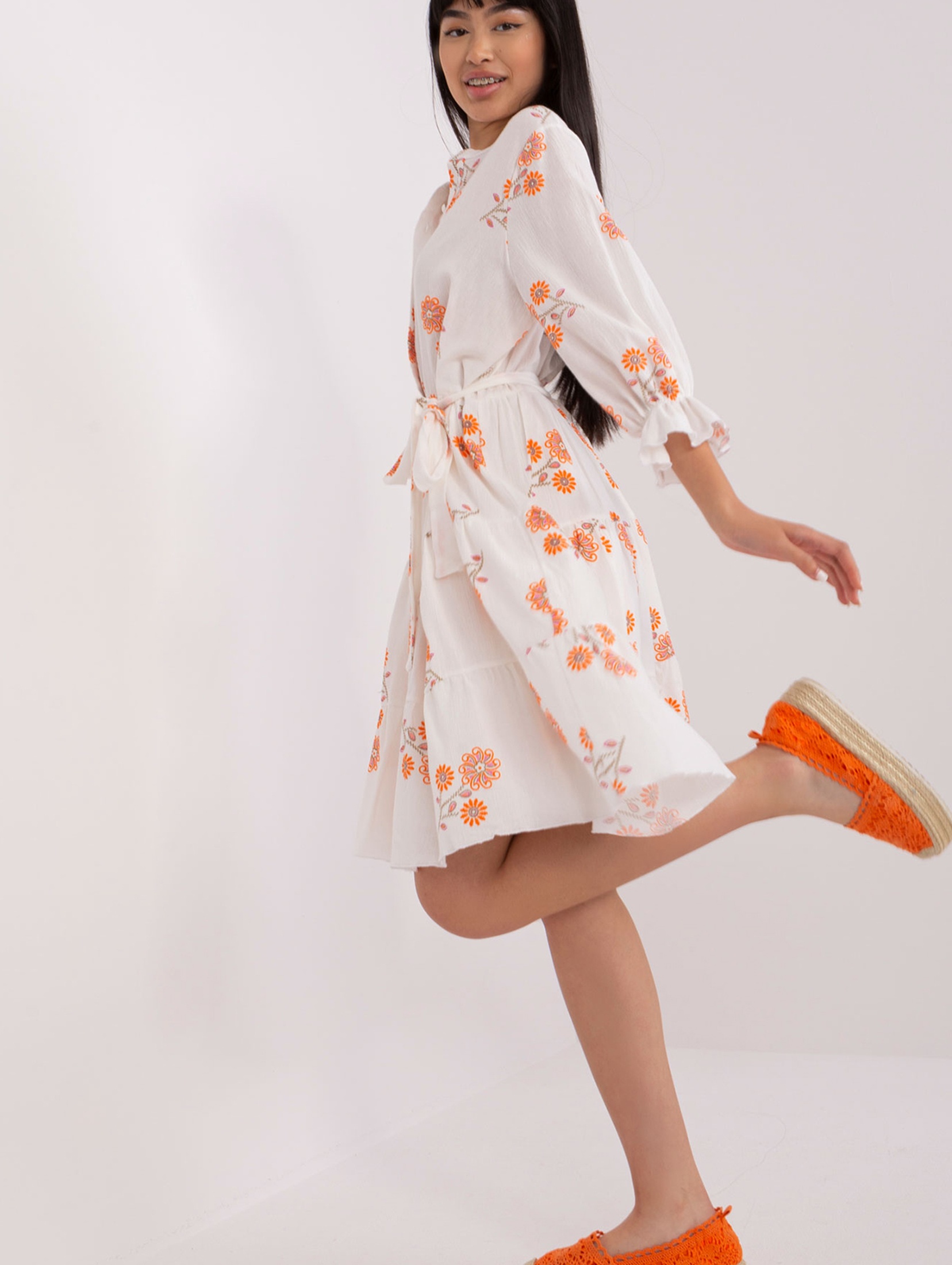 Biało-pomarańczowa wzorzysta sukienka z falbaną